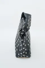 Cartera negra con diseño de tachas plateadas en toda la superficie y una correa de hombro.