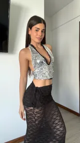 Pollera larga de encaje semitransparente, ajustada al cuerpo y con caída hasta el piso. Presenta frunce regulable con lazo lateral.