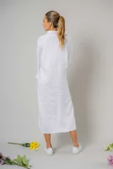 Túnica blanca estilo camisa, larga hasta la rodilla, con cuello clásico, abotonada al frente y aberturas laterales.