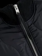 Campera acolchada de color gris oscuro, con diseño matelaseado de ondas, cuello alto en rib, cierre frontal con cremallera metálica y bolsillos frontales aplicados.