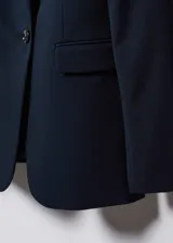 Blazer sastre azul marino de corte entallado, con solapas de muesca, hombros estructurados, cierre de un botón y bolsillos de ribete delanteros.