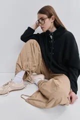 Pantalón cargo negro de corte relajado y pierna ancha con bolsillos laterales con solapa, cintura con doble broche y cierres metálicos en los tobillos.