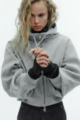 Cazadora de estilo deportivo con capucha ajustable, cierre frontal de doble cremallera y mangas abullonadas con puños elásticos. Presenta bolsillos delanteros y bajo elástico.