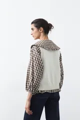 Chaleco tejido de punto color marrón oscuro, con botones frontales y diseño de punto calado vertical.