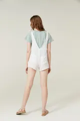 Mono corto color amarillo pastel, con breteles finos que se atan en los hombros, escote recto y dos bolsillos delanteros.