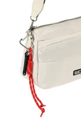 Bandolera negra con correa ajustable, cierre de cremallera en el compartimento principal y bolsillos frontales. Incluye un detalle de cordón rojo y un llavero en espiral negro.