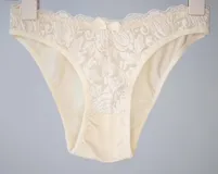 Bombacha de bikini tiro bajo/medio, color negro, confeccionada con tela que contiene fibra LYCRA® y frente de puntilla elastizada.