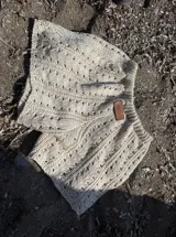 Short de tejido de punto crochet color beige, de cintura elástica y diseño holgado, con detalle de etiqueta de cuero de la marca Antonia Wool Wear en la cintura.