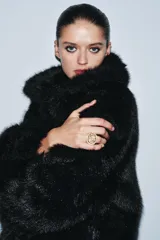 Anillo de metal dorado con banda texturizada y chatón rectangular incrustado con múltiples piedras negras.