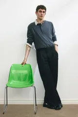 Pantalón sastrero negro de corte holgado, con pinzas frontales y pliegues marcados en las piernas. Presenta pretina con cierre oculto de botón y corchete, bolsillos al bies y bolsillos traseros insertados.