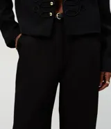 Pantalón de sastrería color negro con corte recto y estructura firme. Presenta cintura con pasadores, cierre frontal y bolsillos traseros embutidos. Incluye un cinturón fino con hebilla metálica.