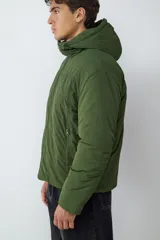 Campera acolchada color verde militar, con capucha integrada, cierre frontal de cremallera y mangas largas. Diseño funcional y versátil para uso diario.