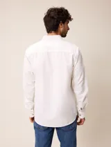 Camisa de manga larga confeccionada en algodón oxford, con cuello abotonado y cierre frontal de botones. Presenta un diseño clásico y minimalista con un pequeño logo bordado en el pecho.