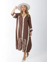 Vestido camisero marrón con rayas verticales color crema, de corte recto y largo midi. Presenta cuello en V, cierre frontal con botones y bordados en el ruedo.