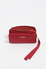 Billetera compacta de estructura blanda en color turquesa, con cierre de cremallera superior y logo metálico dorado en el frente.