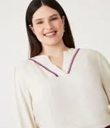 Blusa amplia color crema en viscosa con escote V con detalle de bordado en el escote, manga larga y elástico en el puño.
