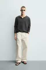 Camiseta de manga larga con corte relajado, confeccionada en algodón. Presenta un cuello redondo amplio con acabado irregular y detalle de botones frontales a tono.