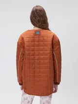 Campera reversible capitoneada con cierre frontal. Un lado es de color negro y el otro es de color beige, ambos con diseño acolchado. Cuenta con cuello redondo, mangas largas y bolsillos laterales.