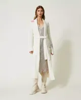 Maxi cárdigan tejido color crema con bordados florales y cinturón.