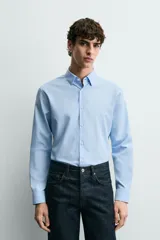 Camisa de corte slim fit, color negro, con cuello italiano, manga larga con puños abotonados y cierre frontal de botones. Confeccionada en tejido de fácil cuidado que minimiza la necesidad de planchado.