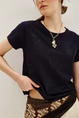 Remera de algodón color azul marino con cuello redondo y mangas cortas. Presenta un estampado de corazones formados por pequeñas aplicaciones brillantes distribuidas por toda la prenda.
