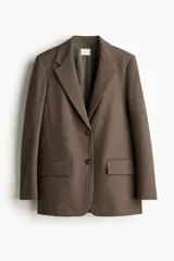 Blazer largo de color marrón, con solapas de muesca, botonadura sencilla y dos bolsillos delanteros con solapa. Presenta forro interior.