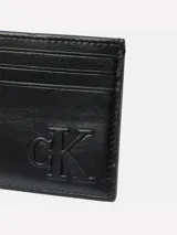 Tarjetero de piel color negro con múltiples ranuras para tarjetas. Presenta el monograma 'CK' en relieve en la parte frontal.