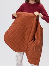 Campera reversible capitoneada con cierre frontal. Un lado es de color negro y el otro es de color beige, ambos con diseño acolchado. Cuenta con cuello redondo, mangas largas y bolsillos laterales.