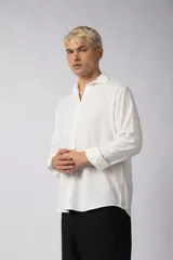 Camisa de manga larga con cuello clásico y cierre frontal de botones. Presenta un calce relajado y una textura liviana.