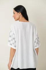 Blusa negra de viscosa con estampado de flores blancas en las mangas, corte holgado, cuello redondo y botones frontales.