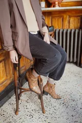 Botas de cuero con estampado de serpiente en tonos marrones y bordeaux, con brillo dorado. Diseño de punta alargada y cierre lateral. Taco bajo de 2.5 cm.