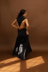 Conjunto de top y falda larga de punto color negro con textura acanalada. El top es corto, sin mangas y con escote en V. La falda es de corte sirena con cintura alta con detalle de ondas.