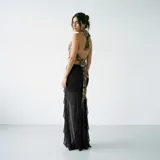 Falda larga negra de corte sirena, con diseño de volados laterales y transparencias en la parte inferior.
