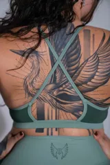 Top deportivo verde oscuro de doble tela, con cuello halter, espalda cruzada y banda elástica inferior en tono más claro. Cuenta con el logo de la marca estampado en el centro del pecho.