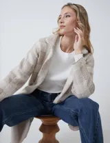 Chaqueta de tejido suave con estampado a cuadros en tonos beige y blanco, cuello con solapa y cierre de botón frontal. Incluye bolsillos delanteros.