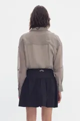 Falda corta de algodón color negro, con volados, cartera de botones frontal y diseño de tiro alto con corte curvo en la cintura.