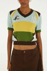 Top tejido de manga corta confeccionado en punto de algodón. Presenta escote en V, diseño de bloques de color en celeste, amarillo, verde y marrón, con detalles bordados en el frente y número 10.