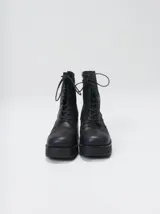 Bota de caña media Mutma modelo Minga, confeccionada en cuero color negro, con diseño acordonado, plataforma, taco ancho y punta cuadrada.