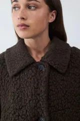 Tapado largo de textura tipo shearling con acabado volumétrico y cálido. Presenta cuello camisero, cierre frontal con botones y un calce relajado.