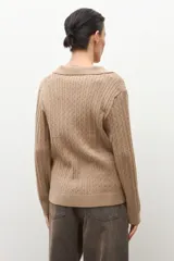 Sweater azul marino de tejido de punto con cuello polo y escote en V. Presenta un diseño de trenzas verticales en toda la prenda y mangas largas.