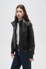 Campera de eco-cuero negro con cuello alto, cierre frontal, bolsillos con solapa en el pecho y puños y ruedo elásticos.