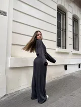 Conjunto de dos piezas compuesto por un buzo de cuello alto y mangas largas con diseño holgado, y un pantalón a juego. Ambas prendas están confeccionadas en tejido morley elastizado de color negro con un sutil efecto jaspeado.