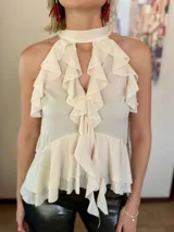 Blusa color marrón chocolate con escote halter, diseño sin mangas y múltiples volados verticales y horizontales que aportan volumen y movimiento.