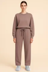 Pantalón jogger color marrón, de corte relajado, con bolsillos laterales aplicados, cintura elástica con cordón de ajuste y botamangas rectas.