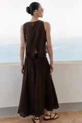Falda midi marrón oscuro, con diseño fluido y voluminoso, tiro alto y detalles de bordados a tono en el ruedo.