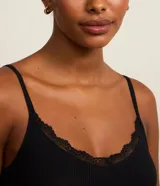 Conjunto de pijama de dos piezas de la marca Lov, compuesto por una musculosa negra de tejido acanalado con escote en V y detalles de encaje, y un short blanco con estampado de lunares negros y cintura elástica.