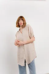 Camisa amarilla de lino, de corte recto y calce suelto. Presenta cuello camisero, botones en el frente y mangas cortas con presilla y botón.