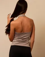 Top color beige con escote halter cruzado y abertura en el centro, con hebillas metálicas.