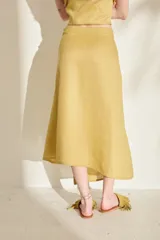 Falda midi verde de lino, con diseño asimétrico, tajito frontal y cierre lateral con botones de madera con ojales bordados.