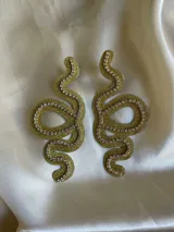 Aros colgantes con forma de serpiente blanca delineada con strass plateado.